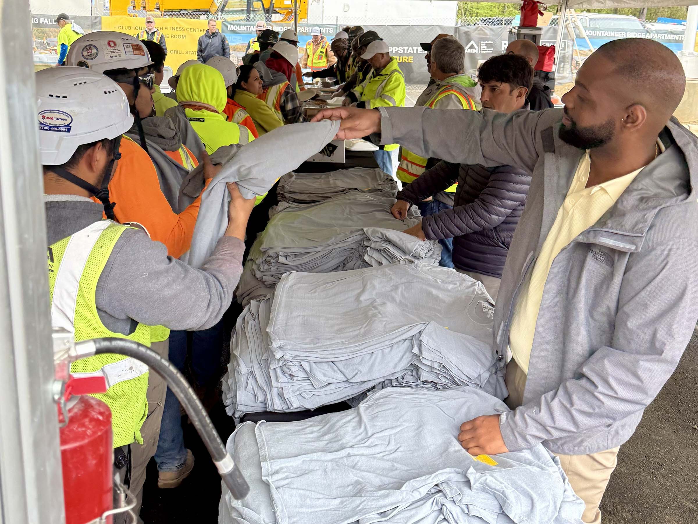 A man distributing commemorative shirts to construction workers